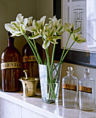 Altmodische Flaschen und Blumenarrangement auf einem Regal