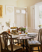 A traditional dining room with wooden table with place settings and a bowl of fruit accompanied by two upholstered chairs