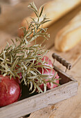 Close up detail of a wooden tray of red onions with a sprig of rosemary