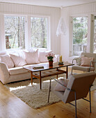 A modern Scandinavian style sitting room with big windows sofa and chairs