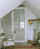 Detail of an interior door next to a gold framed mirror propped up in the corner of a bedroom with a low sloping ceiling