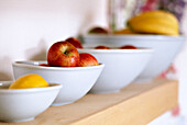 Fruit in ceramic bowls on wooden shelf