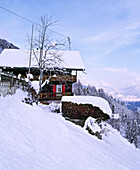 Außenansicht eines schneebedeckten Schweizer Chalets in den Bergen