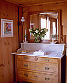 Schweizer Chalet-Schlafzimmer mit Holzvertäfelung und antiker Marmorkommode