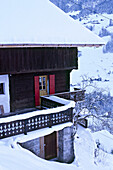 Außenansicht eines schneebedeckten schweizer Chalets mit Balkon