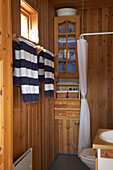 Gestreifte Handtücher hängen auf Handtuchhaltern im holzgetäfelten Badezimmer