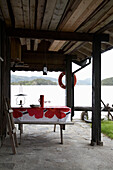 Table and bench seats on covered patio area overlooking lake