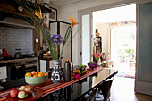 Flower arrangement and bowls of fruit of polished table in contemporary kitchen