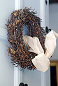 A detail of a Christmas wreath made from twigs hanging on a front door close up