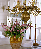 Brass chandelier above ceramic vase with pink flowers