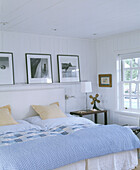Photographs on shelf above double bed with pale blue bedcover