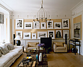 Display of black white photographs above two upholstered armchairs