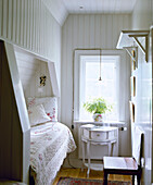 Gustavian side table next to cabin bed in recess in country style bedroom
