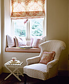 Upholstered armchair next window seat with roller blind