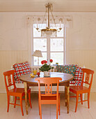 Country style dining room with a lamp suspended over a table surrounded by painted wooden chairs