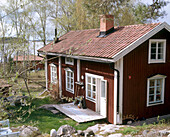 Außenansicht eines traditionellen Holzhauses mit einem See im Hintergrund