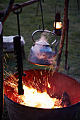 Silberner Wasserkessel über einer Feuerstelle auf dem Gelände eines Schäferwagens, Wiltshire, UK