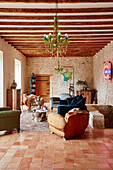 Spacious beamed living room with exposed stone walls and vintage armchairs in Lot et Garonne, France