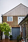 Eingangstüren und Terrassendielen einer umgebauten Scheune bei Regenwetter, Brighton, East Sussex, UK
