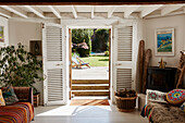 View through white painted double shutters to garden of Bridport home, Dorset, UK