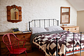 Patchwork quilt on metal framed bed in whitewashed Bridport home, Dorset, UK