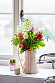 Winter flowers in jug on windowsill in Kent farmhouse, UK