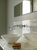 Marble splashback in bathroom with countertop basin and wall tap