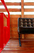 Leather chair on wooden floor laid as a deck with gaps between the boards