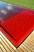 Swimming pool with red venecitas tiling and wooden decking