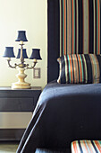 Bedroom with black wood furniture multicoloured hand-woven cloth a cotton bedspread and an antique lamp