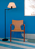 Stuhl und Lampe unter einem Fenster in einer blauen Wand