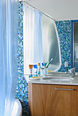 Toiletries on washbasin in tiled bathroom with shower curtain
