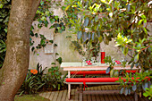 Bench seats with red cushions in walled garden patio