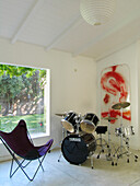 Drum kit and folding chair in playroom with large window and wall mounted art work