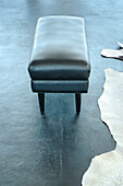Black leather footstool on smoothed concrete floor