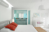 Weiße Piqué-Bettdecke mit roten Kilim-Kissen im Schlafzimmer mit eigenem Carrara-Bad und Hängelampe aus Ripsbändern
