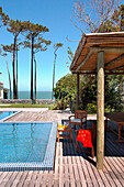 Shaded poolside terrace on beach house exterior with view to sea
