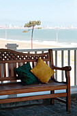 Wooden bench with cushions on coastal exterior balcony