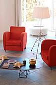 Matching red armchairs in tiled room with floor lamp