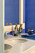 Two figurines under mirror on wash stand