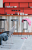 Recycled kitchen counter with Lapacho top and cast iron stools with black leather seats plastered walls painted red