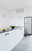 Salad preparation on white panelled units in kitchen with silver fridge
