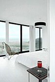 White bedroom interior with large windows and view to sea