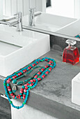 Türkisfarbene Halsketten auf einem Waschbecken mit Betoneinfassung