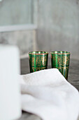 Two green and gold lustre glasses with hand towel in bathroom