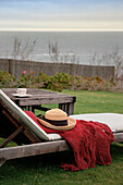 Sunhat and shawl on sunlounger with coastal view