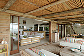 Sofas on beach house deck with view through patio doors to interior