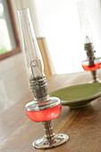 Red glass and metal lanterns on tabletop with ceramic bowl