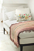 White day bed with floral cushion and striped rug