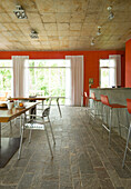 Rote offene Küche mit Fliesenboden und großen Vorhangfenstern
